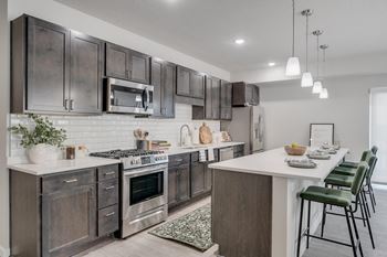A modern kitchen with dark brown cabinets and stainless steel appliances.